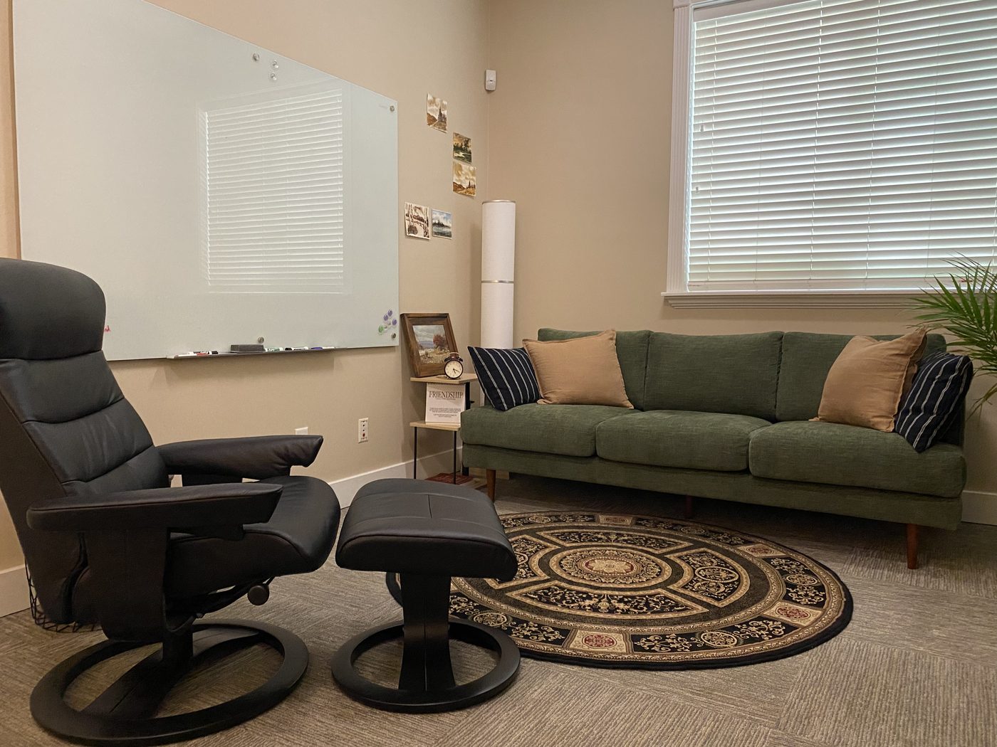 A calm therapy office with a green sofa, reclining chair, and warm natural light